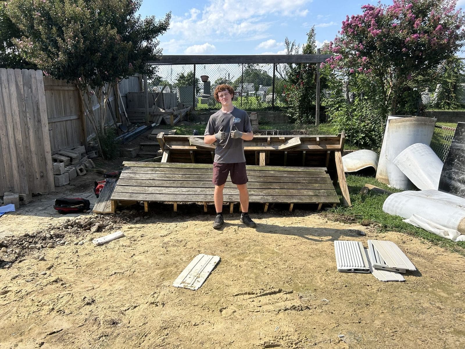 A crew member standing on a backyard deck being taken apart